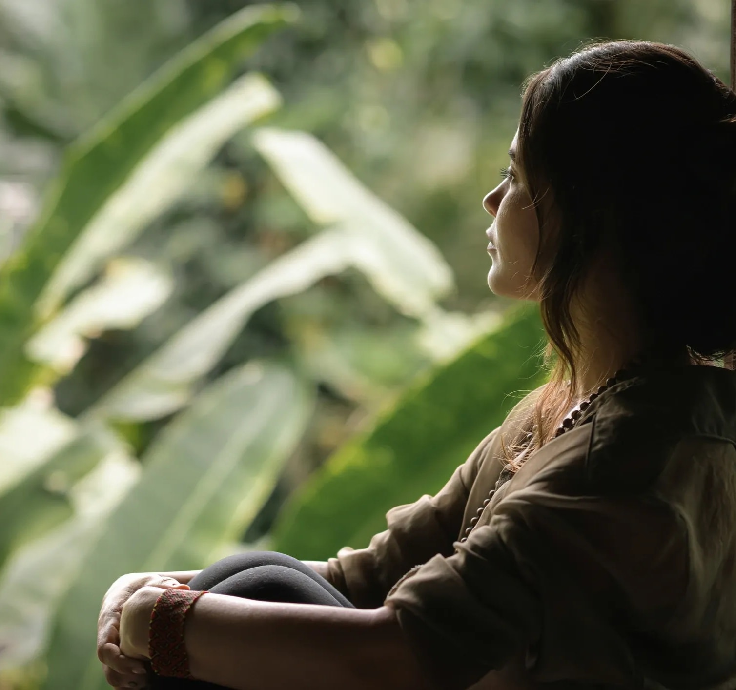 Woman gazing out a window in soft light, reflecting on life transitions